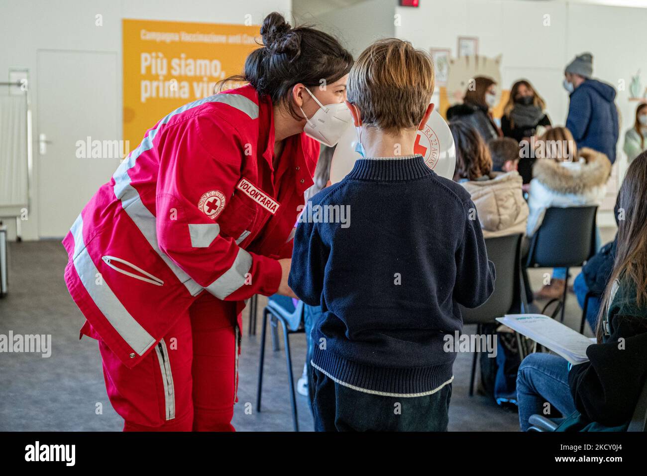 A child plays with a balloon made by a Red Cross volunteer while waiting to receive a dose of the Pfizer COVID-19 vaccine at the Brescia Children's Vaccine Hub during the national open day. (Photo by Stefano Nicoli/NurPhoto) Stock Photo