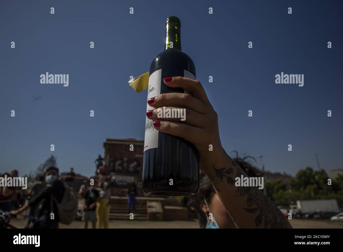 A person holds a bottle of wine while celebrating the death of Lucia Hiriart (99), widow of dictator Augusto Pinochet. On December 16, 2021. Santiago, Chile. (Photo by Claudio Abarca Sandoval/NurPhoto) Stock Photo