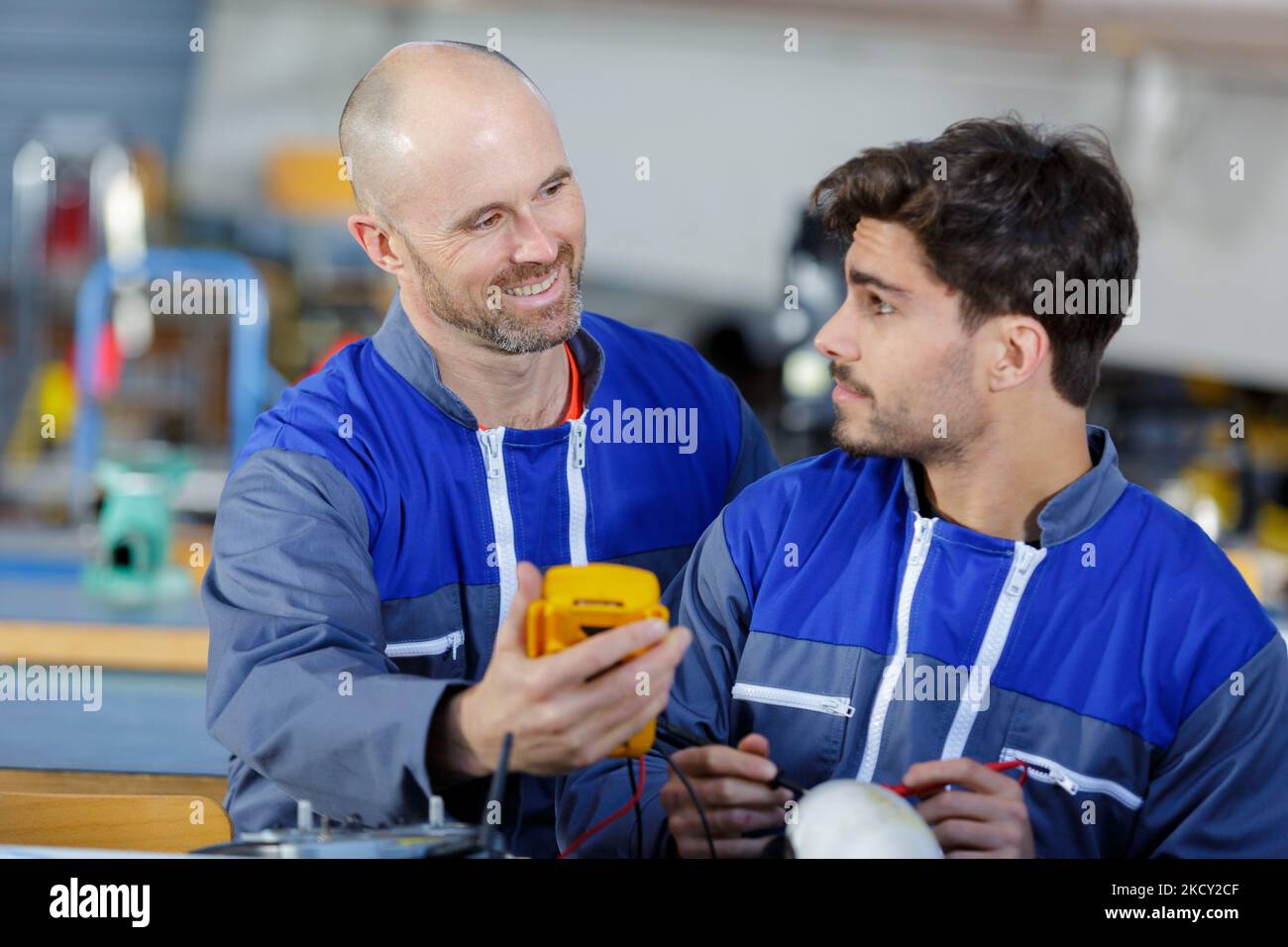 supervisor training apprentice using multimeter in factory Stock Photo