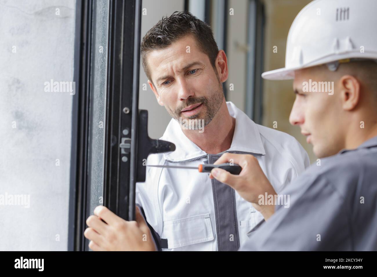 repairman fixing window with screwdriver Stock Photo - Alamy