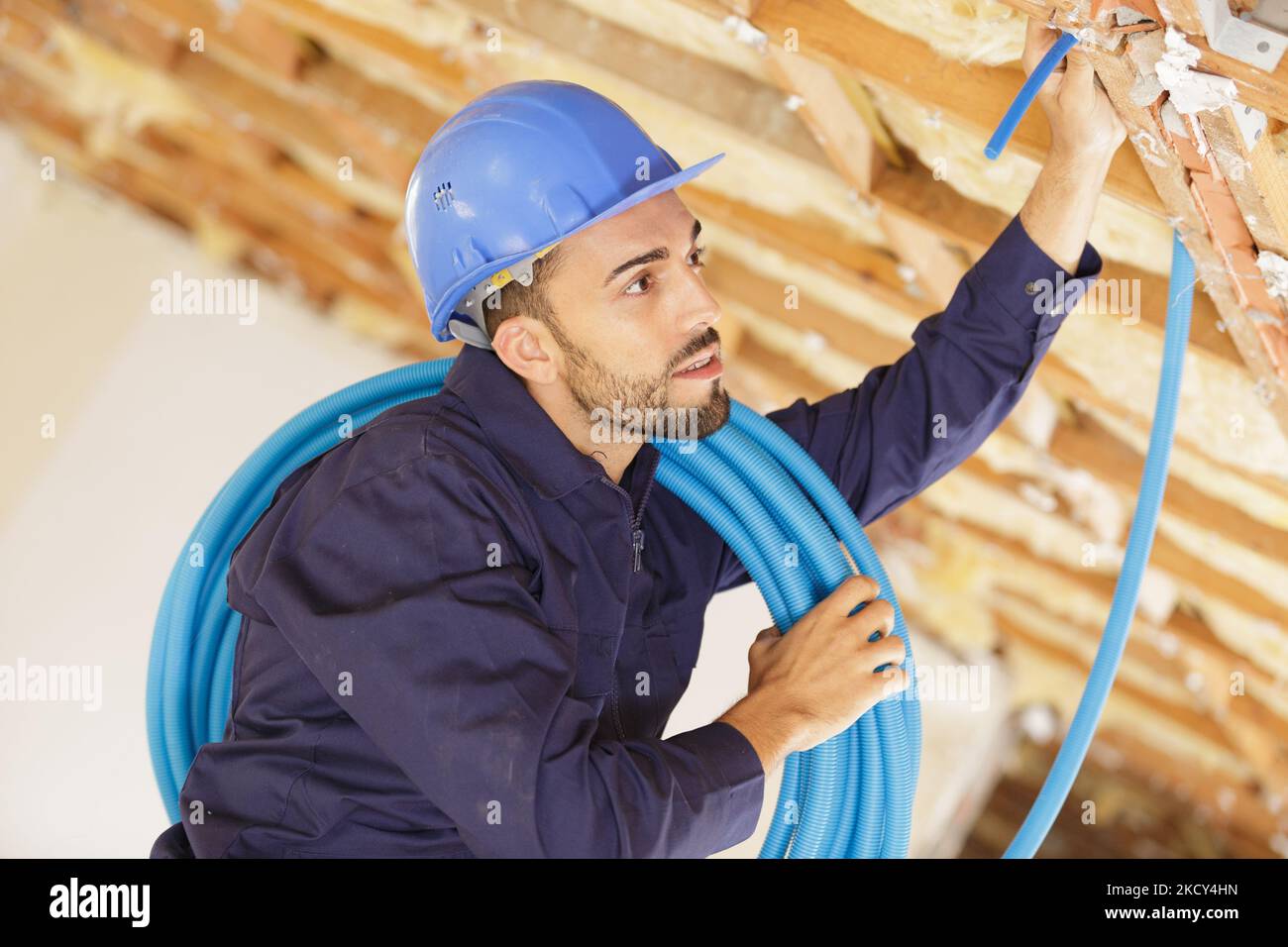 builder threading cables through wall Stock Photo Alamy