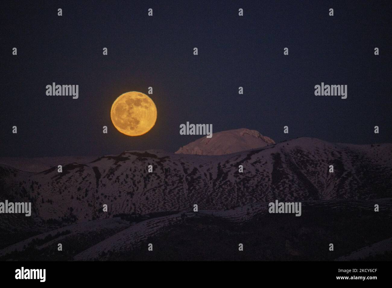 Cold moon rises at sunset behind Monte Camicia mountain in Gran Sasso National Park in Italy, on december 19, 2021. The 'micro moon' is the last full moon of the year. (Photo by Lorenzo Di Cola/NurPhoto) Stock Photo