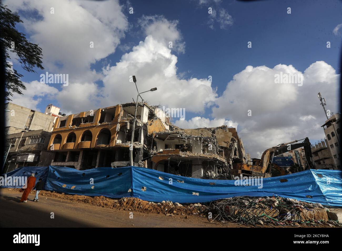Palestinian workers remove the rubble of al-Jawhara Tower in Gaza City ...