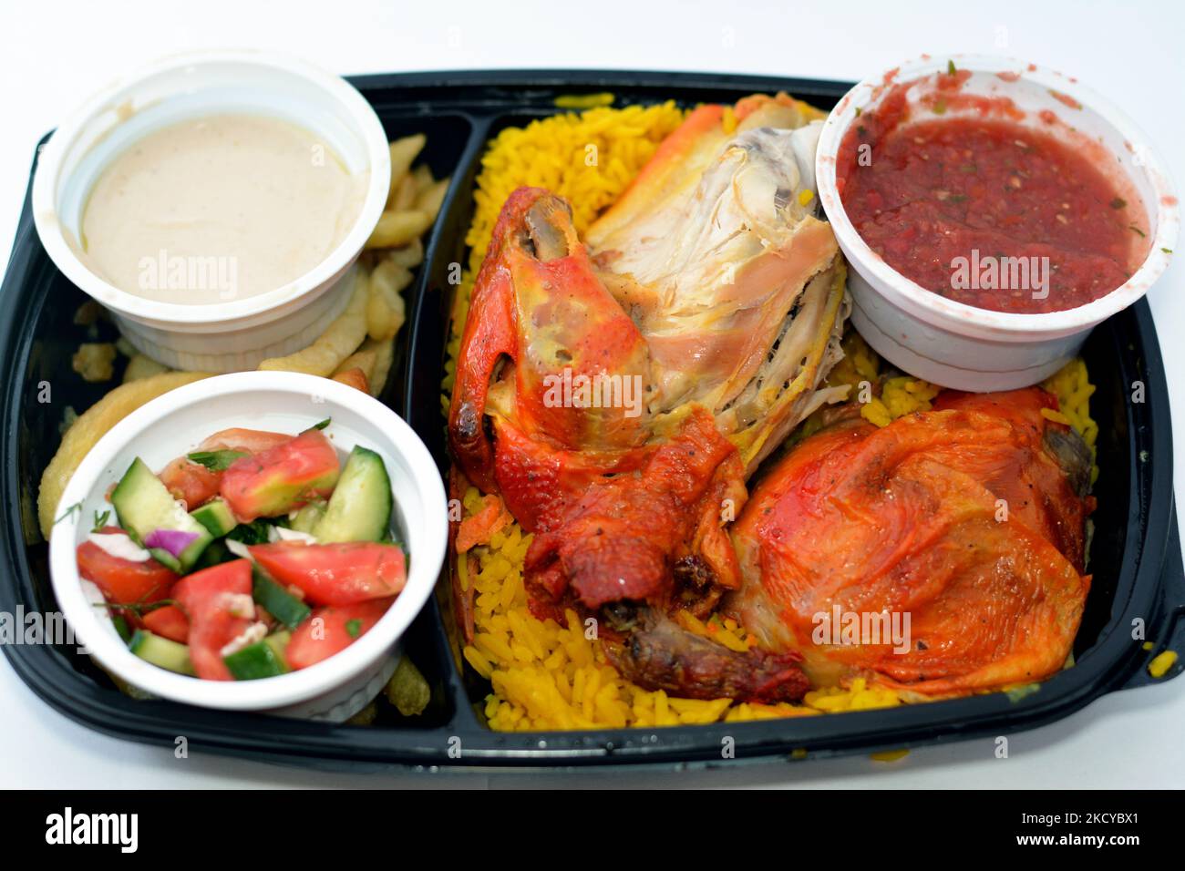 Chicken mandi kabsa with long basmati rice and french fries, served with tomato dakos sauce, green salad and tahini, selective focus of Yemen recipe o Stock Photo