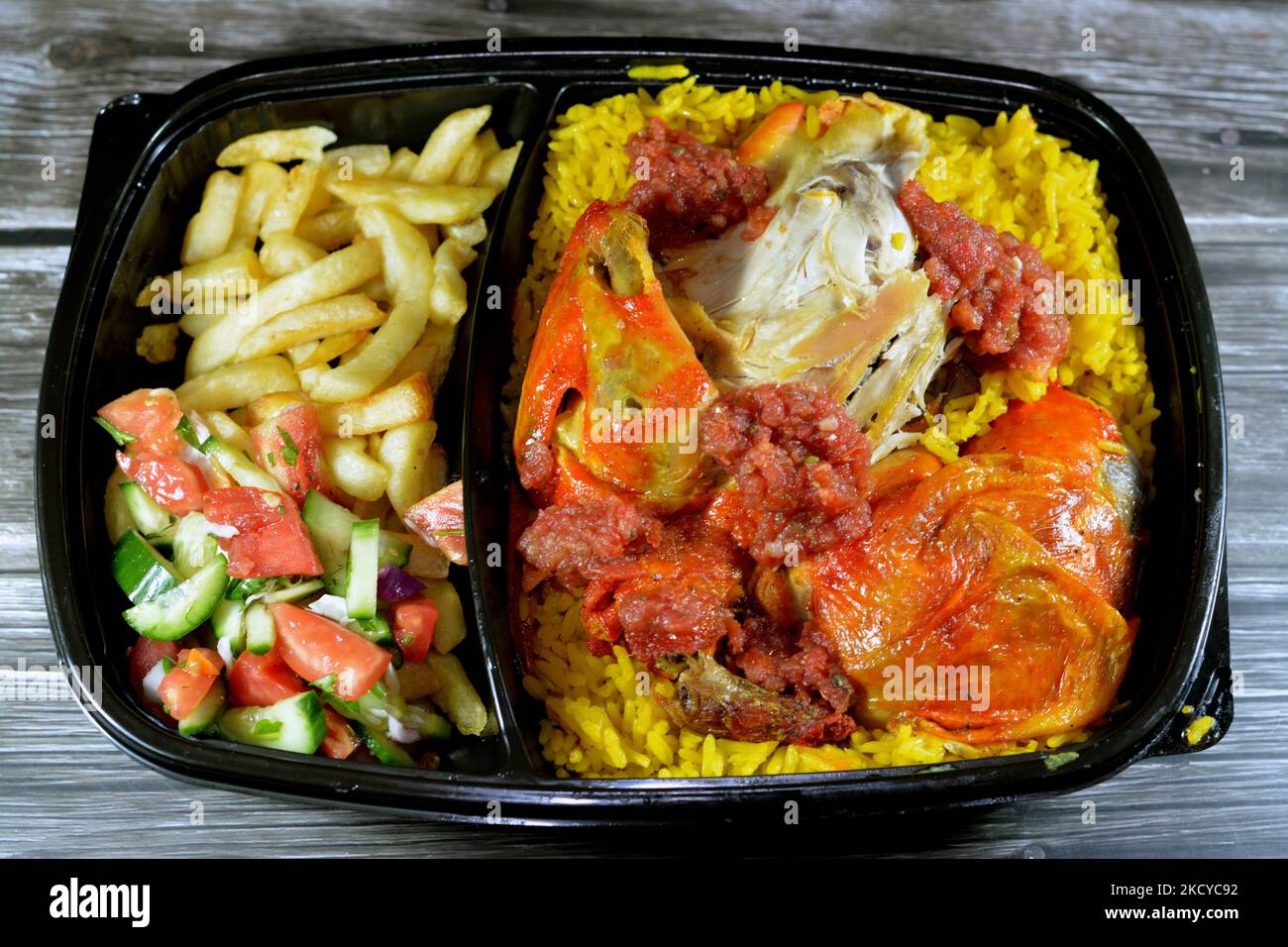 Chicken mandi kabsa with long basmati rice and french fries, served with tomato dakos sauce and green salad, selective focus of Yemen recipe of Mandi Stock Photo