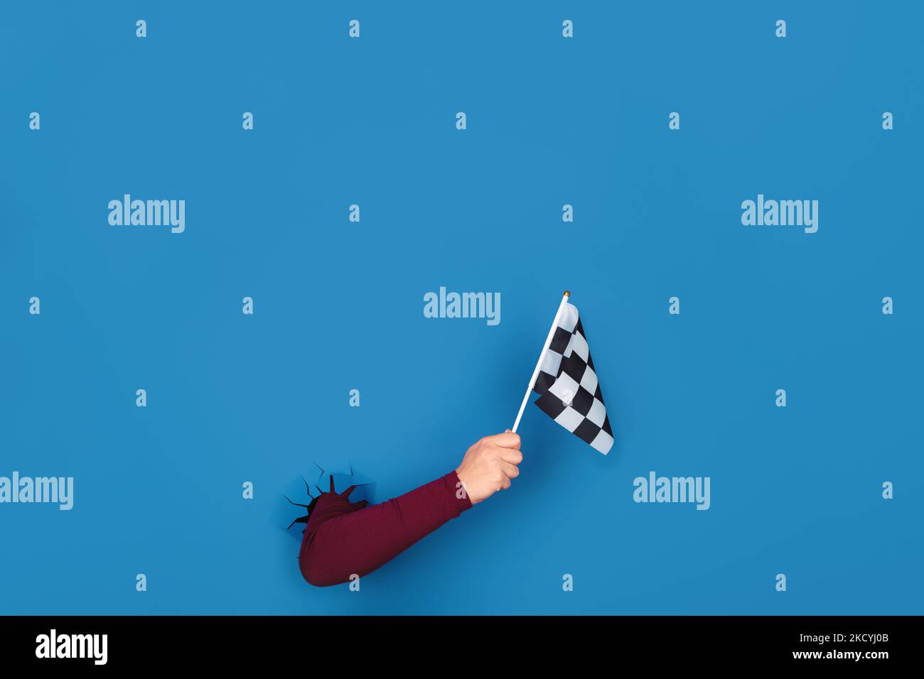 hand holding checkered flag over blue background Stock Photo