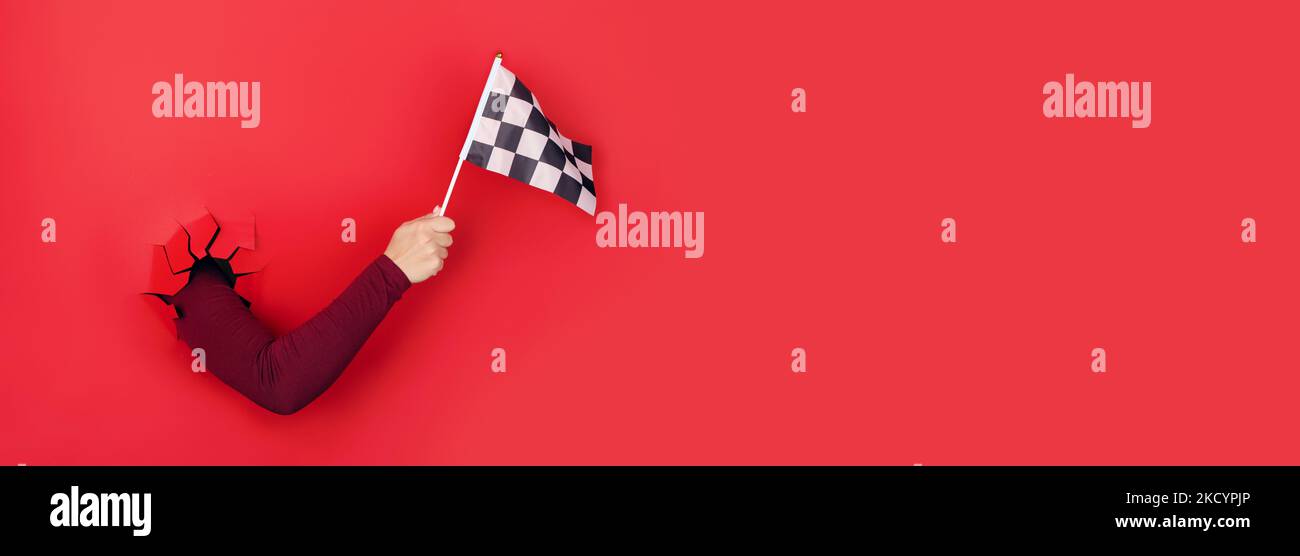 checkered flag in hand over red background, panoramic layout Stock Photo