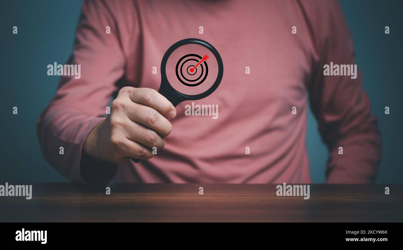 Target inside magnifier glass for focus business objective, hand of