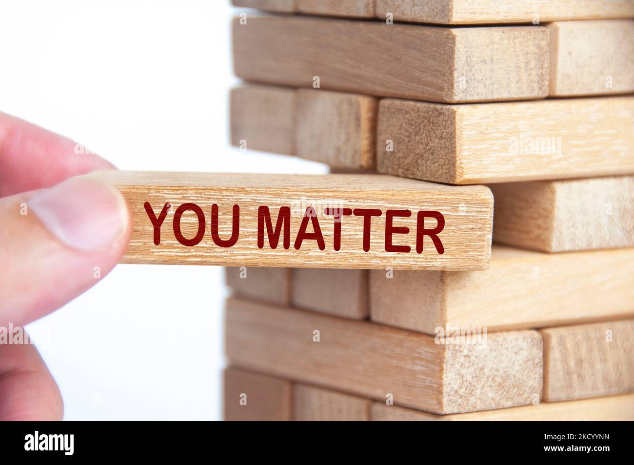 Hand holding a wooden block with text - You Matter to stabilize the entire wooden stacks. Inspirational concept. Stock Photo