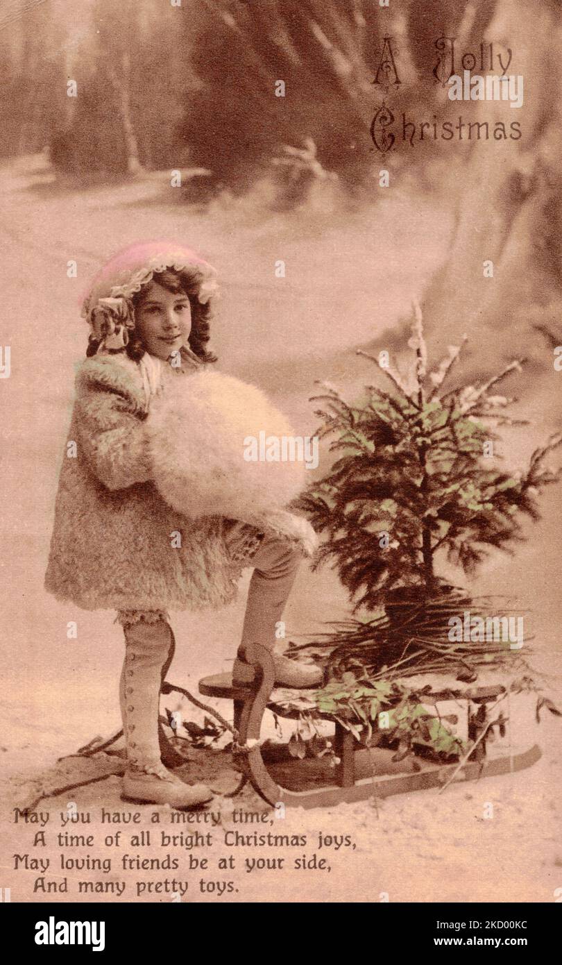 A Jolly Christmas - Sepia Christmas postcard depicting a young girl, a sleigh and a holly, circa1915 Stock Photo