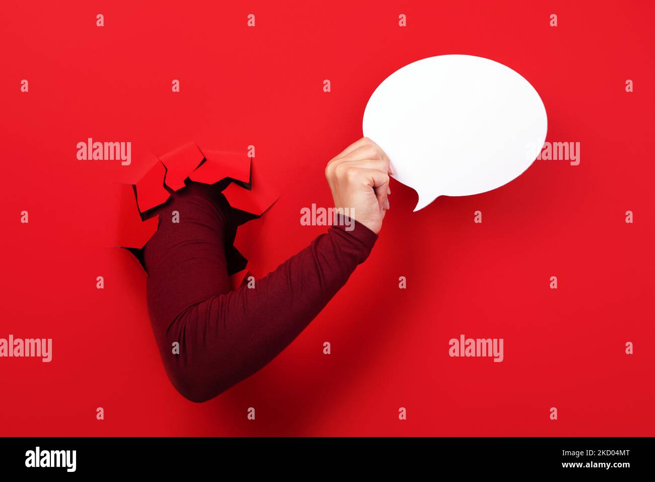 Talk bubble speech icon in hand over red background Stock Photo