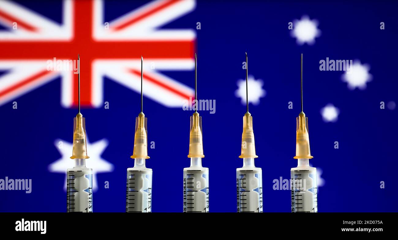 Medical syringes and Australian flag displayed in the background are seen in this illustration photo taken in Krakow, Poland on January 11, 2022. (Photo by Jakub Porzycki/NurPhoto) Stock Photo