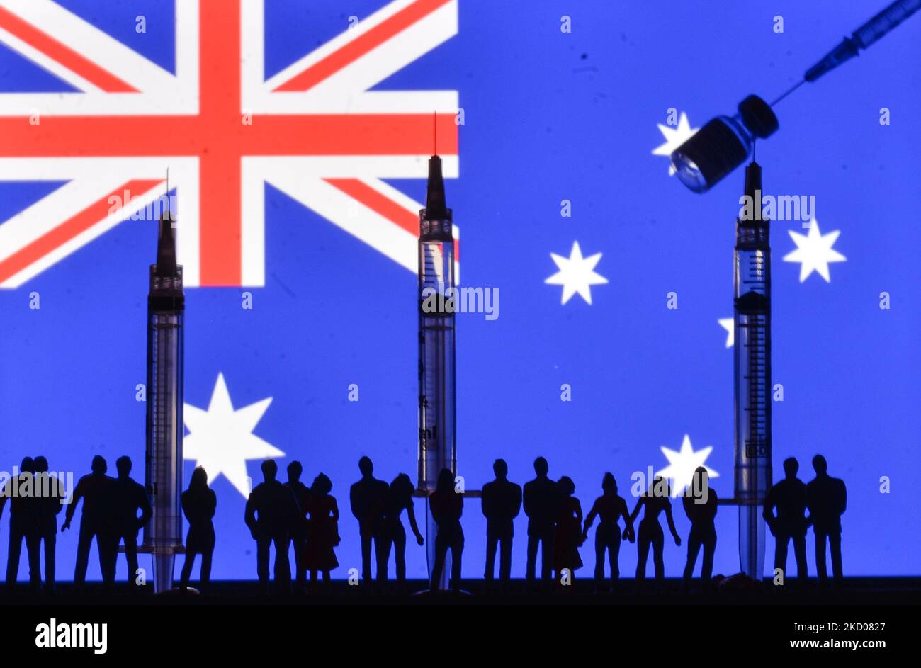 Illustrative photo of medical syringes and small figurines of people waiting in line for the Covid-19 vaccine booster, in front of the flag of Australia displayed on a computer screen. On Tuesday, January 11, 2021, in Edmonton, Alberta, Canada. (Photo by Artur Widak/NurPhoto) Stock Photo