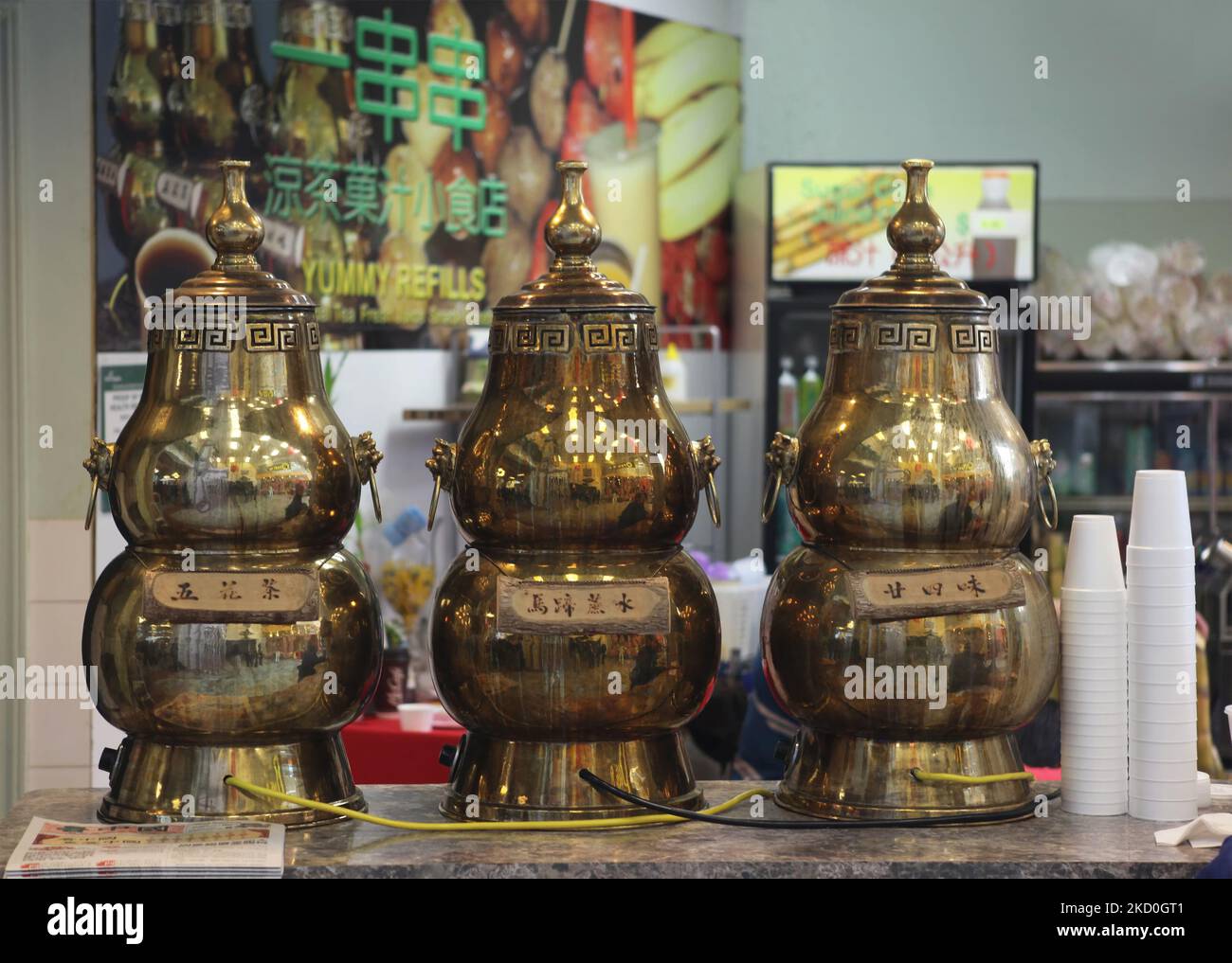 Large brass containers filled with medicinal Chinese herbal tea at a