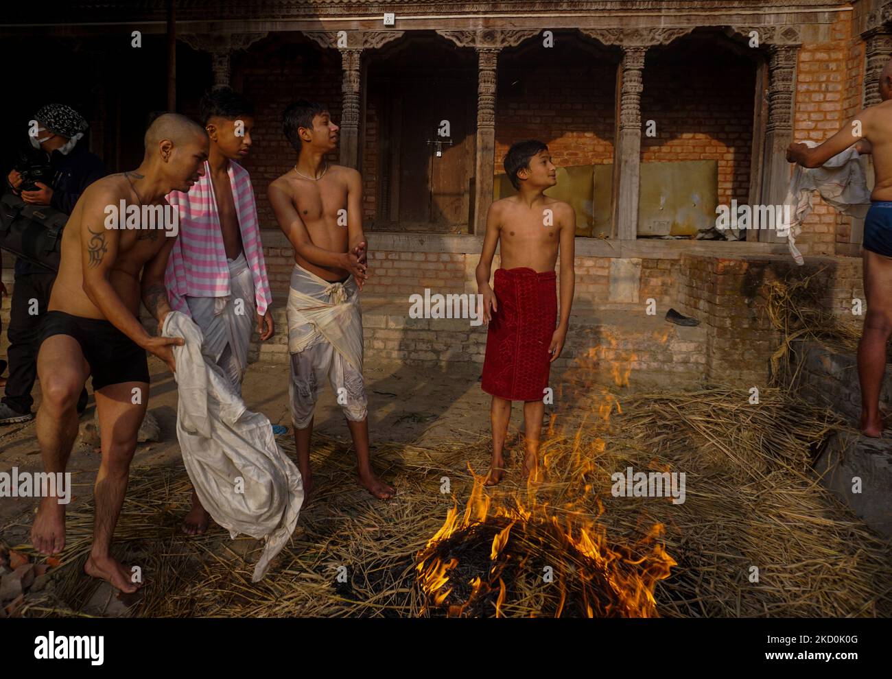 Devotees warm themselves around fire before taking a holy dip in the Hanumante river during the first day of Madhav Narayan Festival in Bhaktapur, Nepal on January 17, 2022. During the festival, devotees recite holy scriptures dedicated to the Hindu goddess Swasthani and Lord Shiva. (Photo by Sunil Pradhan/NurPhoto) Stock Photo