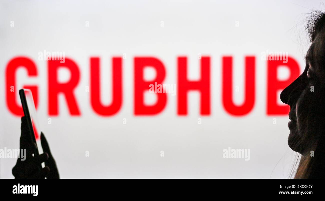 An image of a woman holding a cell phone in front of a Grubhub logo displayed on a computer screen. On Tuesday, January 12, 2021, in Edmonton, Alberta, Canada. (Photo by Artur Widak/NurPhoto) Stock Photo