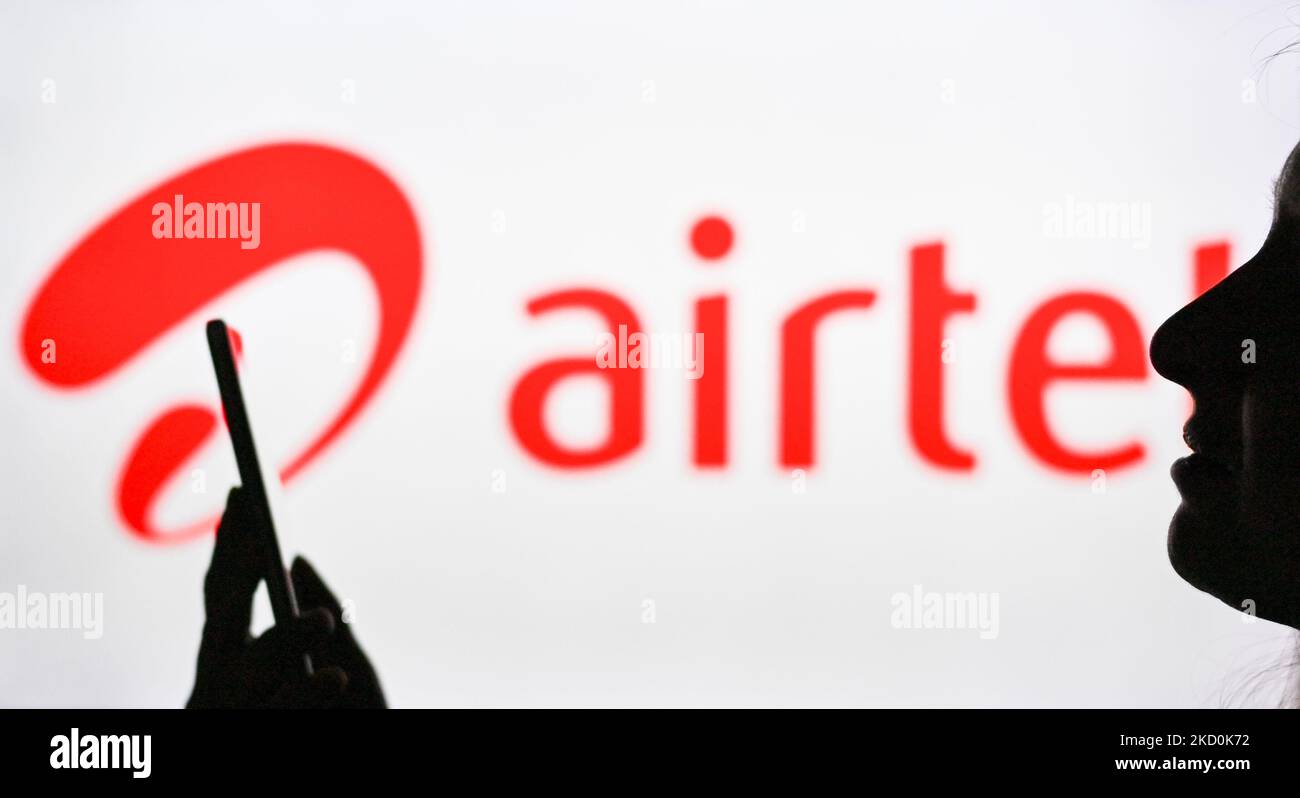 An image of a woman holding a cell phone in front of the Airtel logo displayed on a computer screen. On Tuesday, January 12, 2021, in Edmonton, Alberta, Canada. (Photo by Artur Widak/NurPhoto) Stock Photo