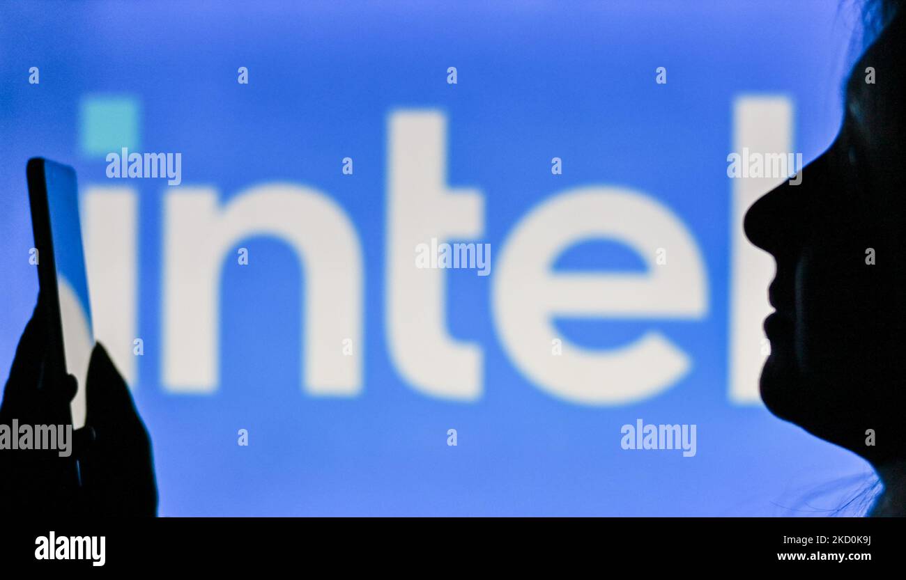 An image of a woman holding a cell phone in front of the INTEL logo displayed on a computer screen. On Tuesday, January 12, 2021, in Edmonton, Alberta, Canada. (Photo by Artur Widak/NurPhoto) Stock Photo
