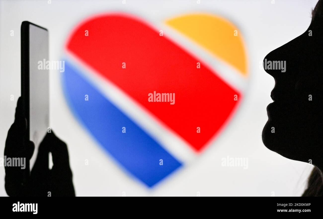 An image of a woman holding a cell phone in front of the Southwest Airlines logo displayed on a computer screen. On Tuesday, January 12, 2021, in Edmonton, Alberta, Canada. (Photo by Artur Widak/NurPhoto) Stock Photo