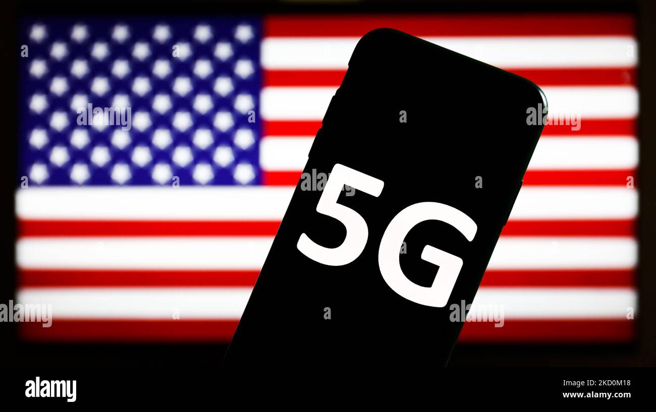 5G sign displayed on a phone screen and American flag displayed on a screen in the background are seen in this illustration photo taken in Krakow, poland on January 18, 2022. (Photo by Jakub Porzycki/NurPhoto) Stock Photo