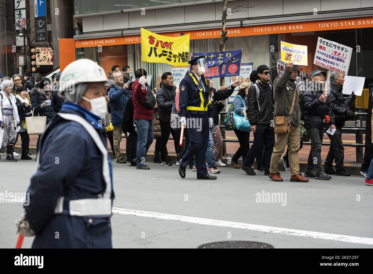 Anti-vaccine protestors rally past an elder traffic guard wearing masks at Shibuya in Tokyo, Jan 23. (Photo by Yusuke Harada/NurPhoto) Stock Photo