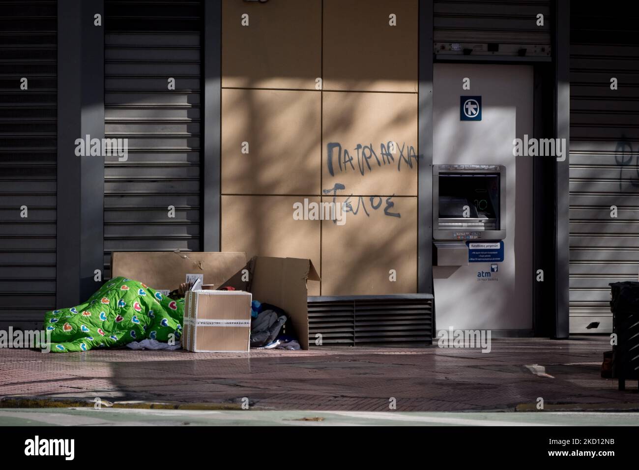 A homeless is sleeping front of a bank in the center of Athens, Greece ...