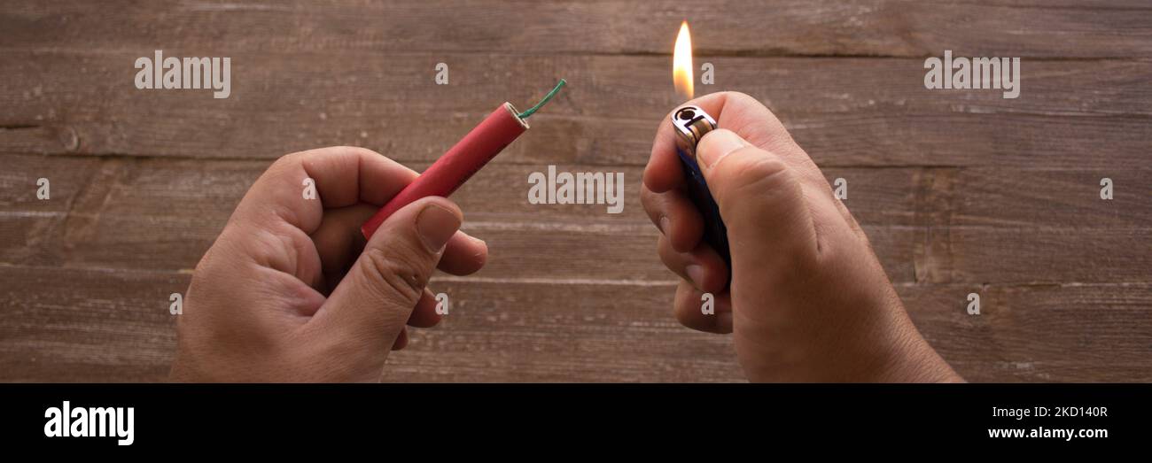 Image of the hands of a man who lights the fuse of a firecracker with a