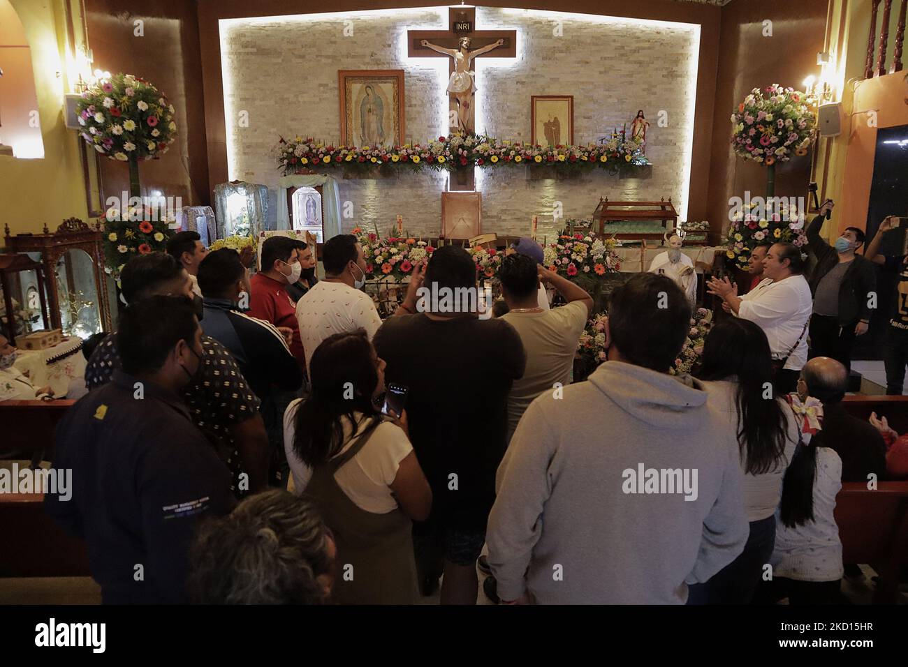 A group of young people pray inside a church before participating in the game called Palo Ensebado or Cucaña, held in the streets of San Antonio Culhuacán in Mexico City to celebrate the patron saint of animals, San Antonio Abad, which took place during the COVID-19 health emergency and the return to the yellow epidemiological traffic light after the increase in coronavirus infections in the capital. This game originated in Naples, Italy, in the 16th century. In its Mexican version, it consists of organising a team of people of different complexions to obtain the prizes that are placed at the  Stock Photo