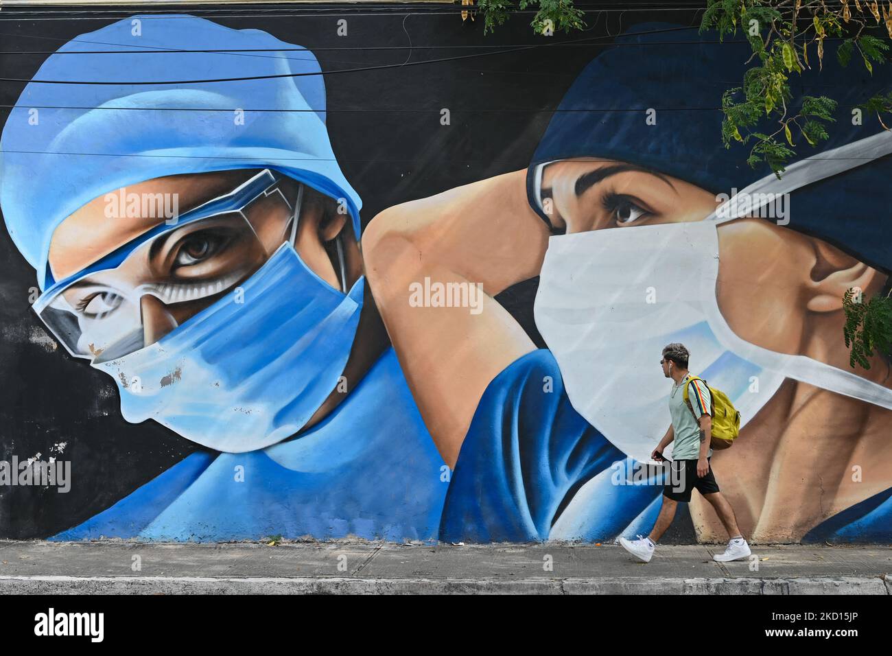 A man walks past a mural of medical workers wearing face masks painted in the center of Merida by Mexican artists Mare - Noookye. On Sunday, January 23, 2022, in Merida, Yucatan, Mexico. (Photo by Artur Widak/NurPhoto) Stock Photo