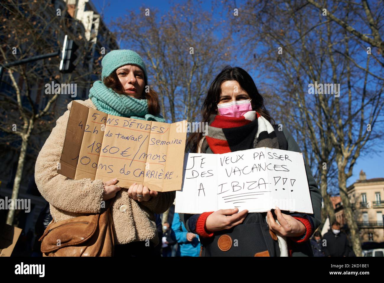 Two woman hold placard reading '5 years of studying, 42h hours per week; €1260 wage, 10 years of career' (Left) and 'I want to go on holidays in Ibiza' (right). Between 3000 and 4000 people demonstrated in the streets of Toulouse called by nearly all trade unions(CGT, FSU, SUD, FO). A lot of people from the National Education were there (teachers, AESH, etc.)still angered by the conduct of Education Ministter J.-M. Blanquer who announced the new sanitary protocols from its holidays in Ibiza the day before the retruen of christmas holidays. Protesters demand better wages, better working conditi Stock Photo