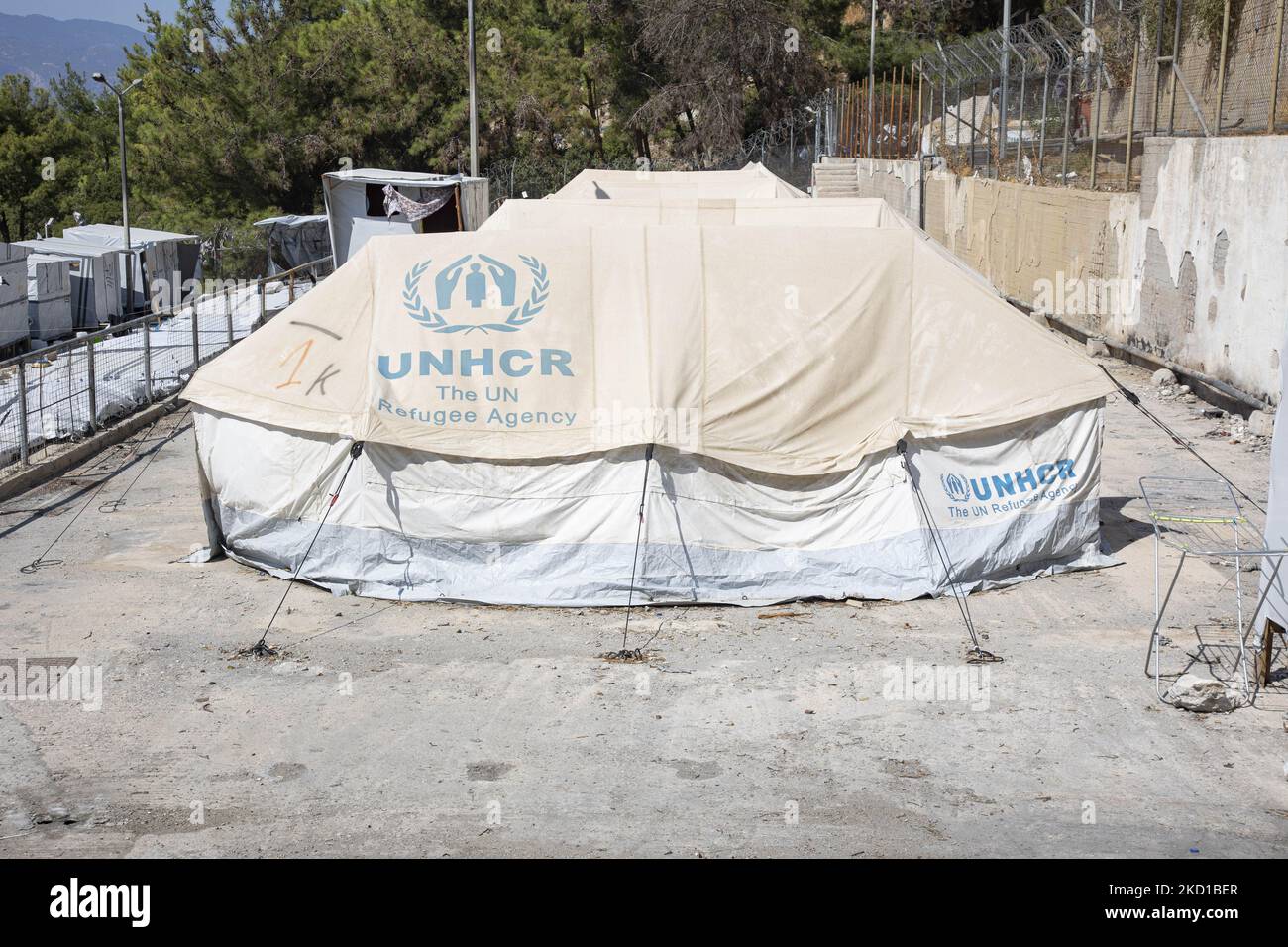 White tents in the official camp with the UNHCR - THE UN Refugee agency logo. The former official refugee - migrant camp surrounded by barbed wire fence at Vathy of Samos Island and the neighboring makeshift camp with handmade tents and some from UNHCR that is located just next to the houses of Vathi town, as seen deserted. The camp has been emptied and people relocated or moved with the police escort to the new camp and some very few houses. Once this facility hosted at its peak 7500 asylum seekers at the official facilities but also the makeshift camp in the forest that was nicknamed The Jun Stock Photo