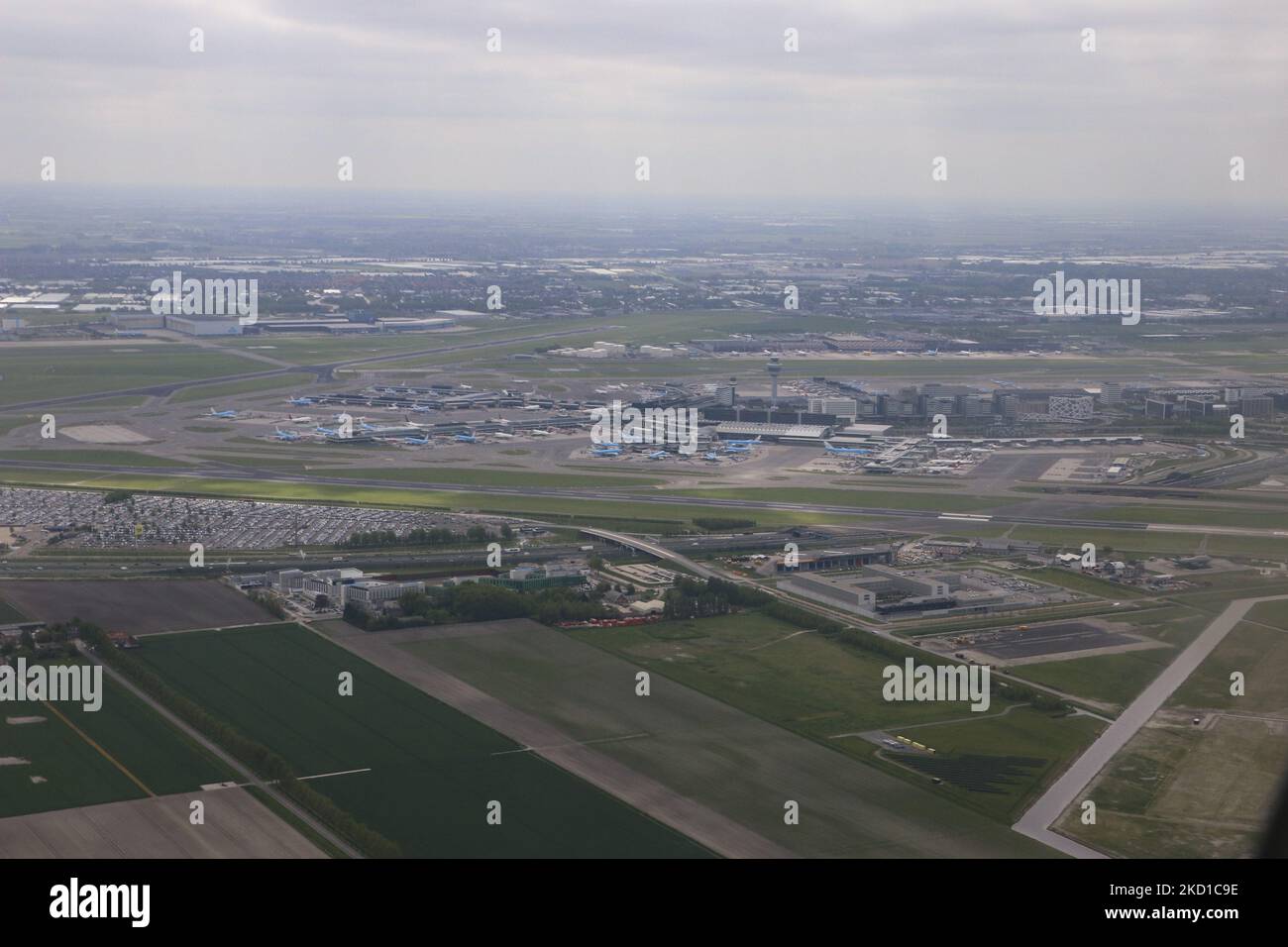 Panoramic aerial view of Amsterdam airport, the terminal, control tower, aircraft, runways, taxiways, parking, dummy testing plane for firefighters and the residential area with houses, roads and canals of the Dutch capital city Amsterdam as seen from an airplane window after takeoff, departing from Polderbaan runway from Amsterdam Schiphol Airport. Amsterdam, the Netherlands on May 4, 2021 (Photo by Nicolas Economou/NurPhoto) Stock Photo