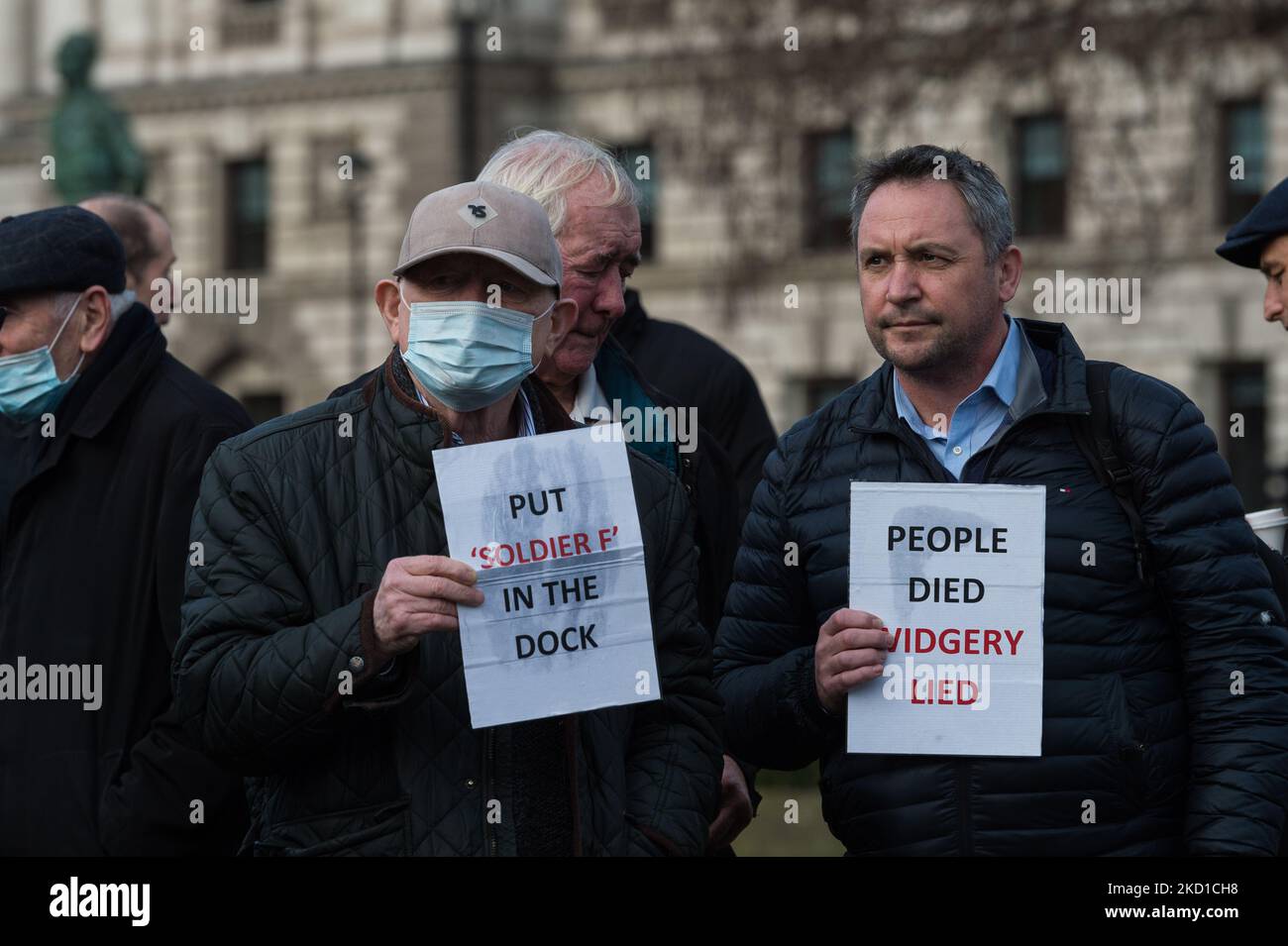 LONDON, UNITED KINGDOM - JANUARY 27, 2022: Men hold placards referring to the case of 'Soldier F' and the initial inquiry into Bloody Sunday by Lord Widgery during a vigil outside Houses of Parliament to commemorate the 50th anniversary of Bloody Sunday and protest against the British government's proposals for the amnesty for the state forces involved on January 27, 2022 in London, England. On Sunday 30 January, 1972, British soldiers opened fire on unarmed civilians taking part in a civil rights march in Derry killing thirteen and wounding fifteen people, with the day becoming known as Blood Stock Photo