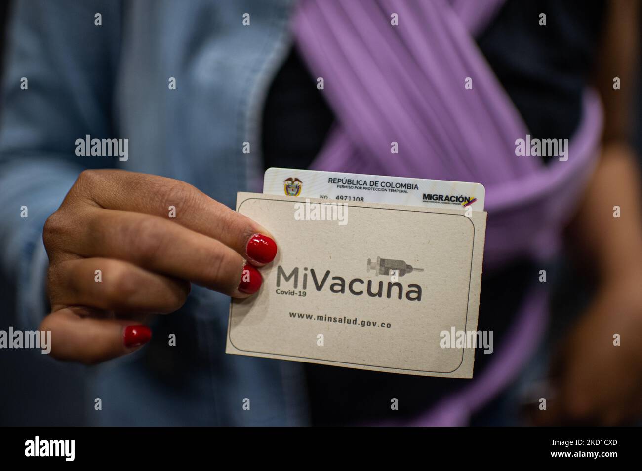 A Venezuelan migrant holds the 'Mi Vacuna' COVID-19 vaccination certificate along the Temporary Residence Permit from Colombia's Migration office on January 27, 2022. Colombia Migration is organizing mass events to grant more than 70.000 temporary permissions ID's to Venezuelan migrants in the span of 7 days. (Photo by Sebastian Barros/NurPhoto) Stock Photo