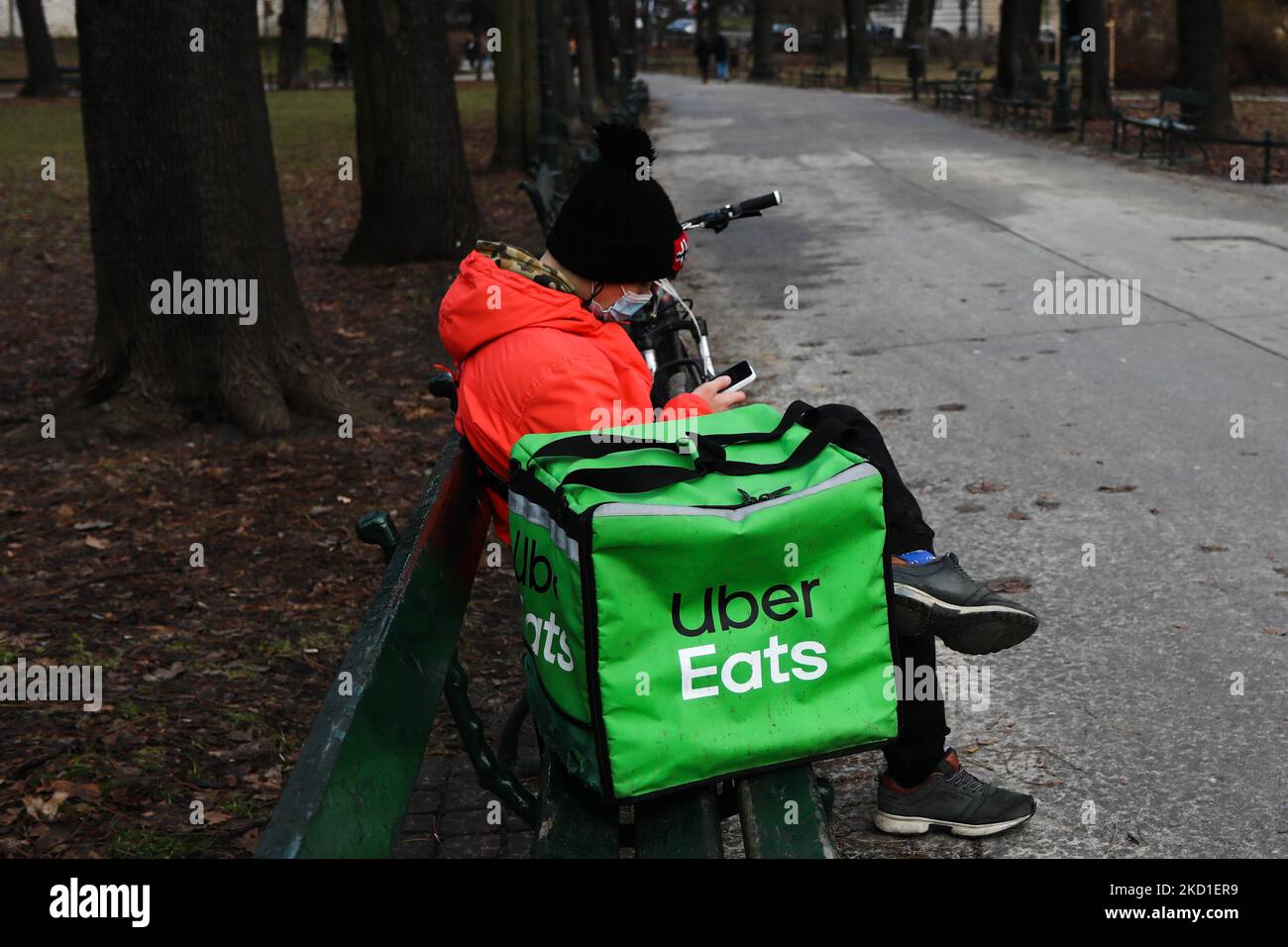 Uber Eats courier sits on a bench in a park in Krakow, Poland on ...