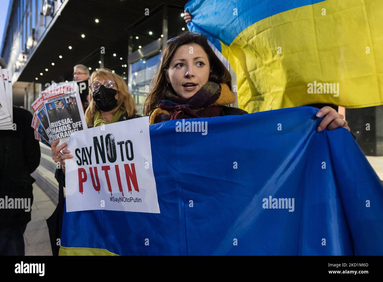 LONDON, UNITED KINGDOM - JANUARY 31, 2022: Protesters hold Ukrainian flags as they demonstrate outside the studios of RT, Russian state-owned international television network, against Russia's military build-up on the border with Ukraine amid rising tensions between East and West on January 31, 2022 in London, England. An estimated 100,000 Russian troops, tanks, artillery and missiles are deployed near the border with Ukraine but the Kremlin denies invasion plans while making demands from NATO last month that Ukraine and other ex-Soviet countries are denied its membership and withdrawal of all Stock Photo