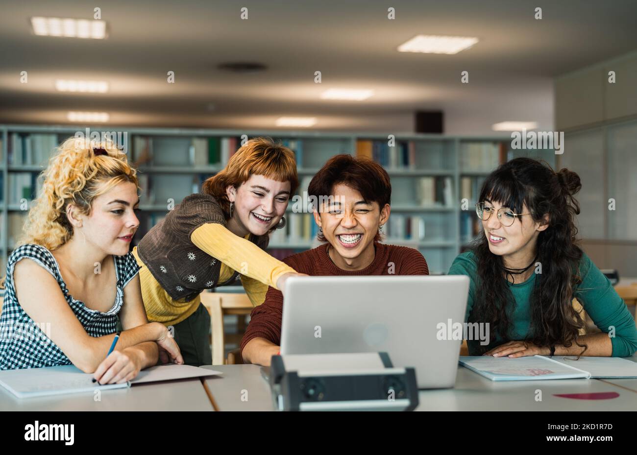 Young university students using laptop and studying with books in library - School education concept Stock Photo