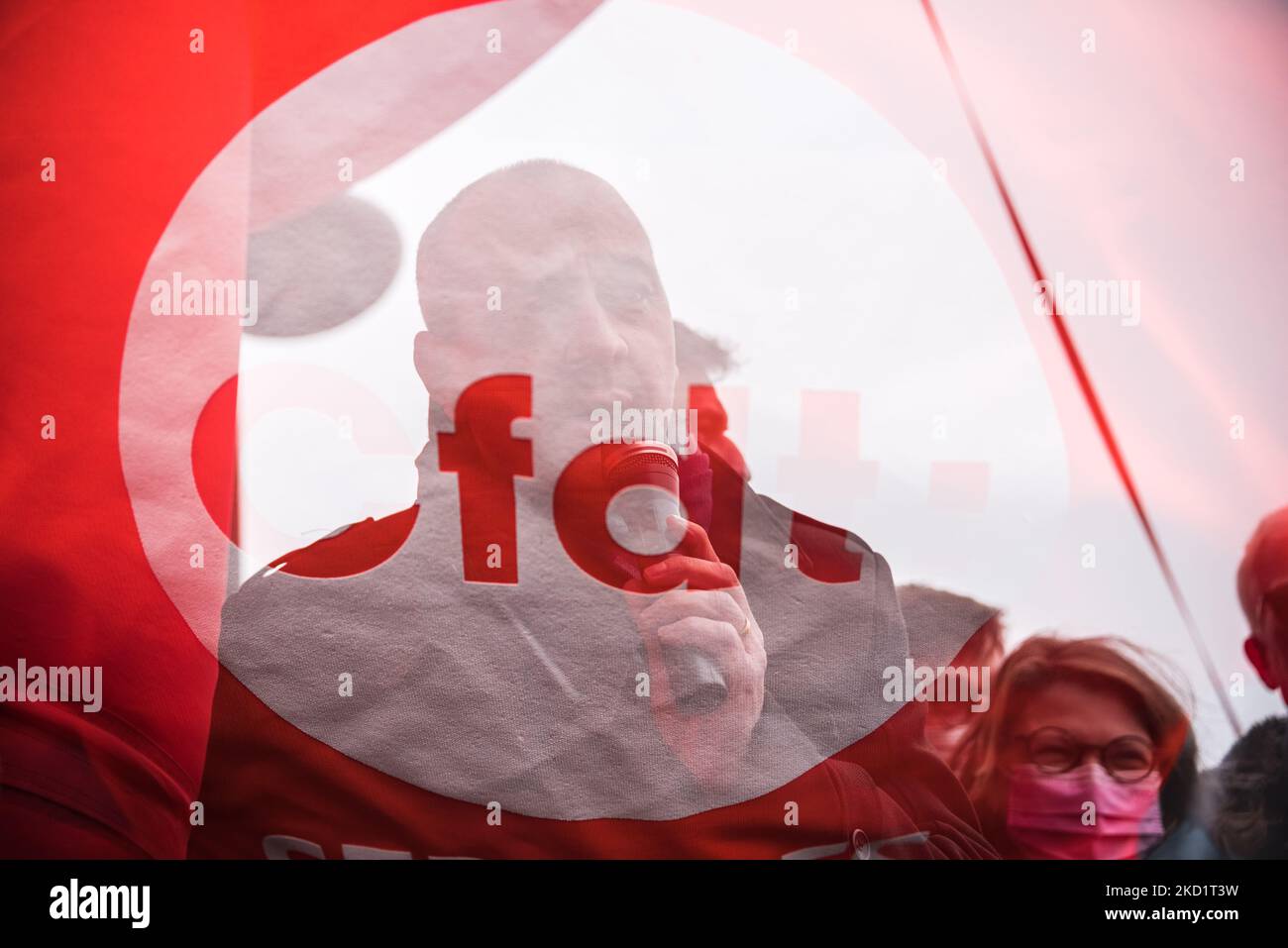 A double exposure of an orange flag and CFDT Secretary General Laurent Berger (Center) making a speech as several hundred CFDT (Confédération Française Des Travailleurs) union activists gathered in Paris in front of the Beaugrenelle shopping mall on February 3, 2022 to participate in the March of Non-Essential Workers organized by the union to demand better wages and working conditions for those on the front lines during the COVID pandemic. (Photo by Samuel Boivin/NurPhoto) Stock Photo