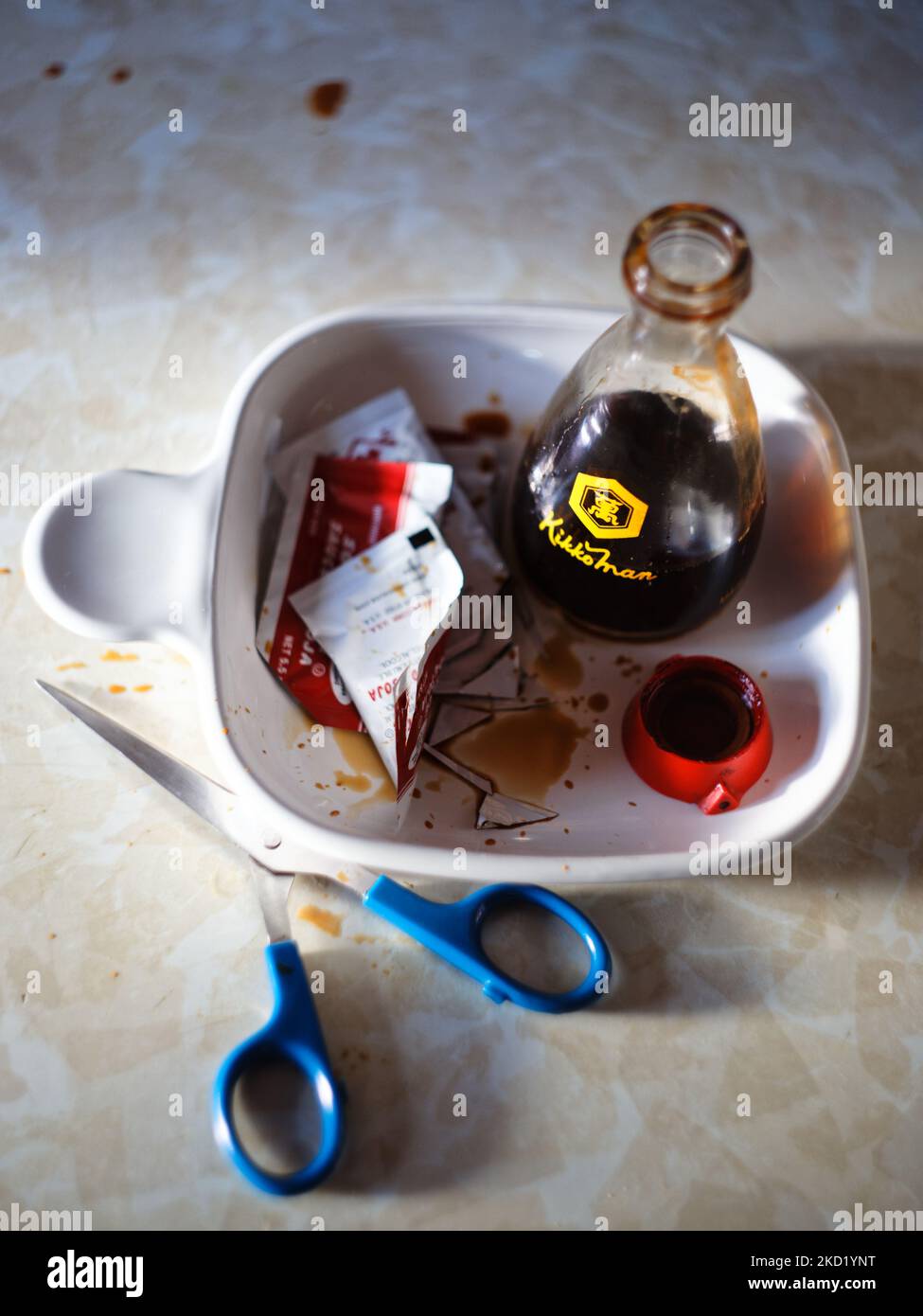 A top view of used condiments in the white can with a scissors on the table Stock Photo