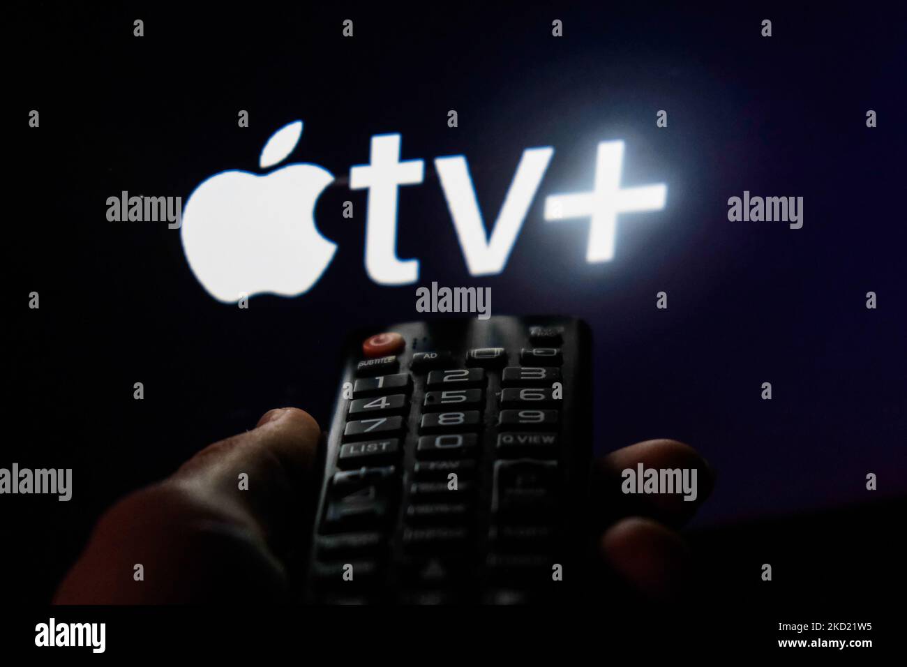 TV remote control is seen with Apple TV+ logo displayed on a screen in