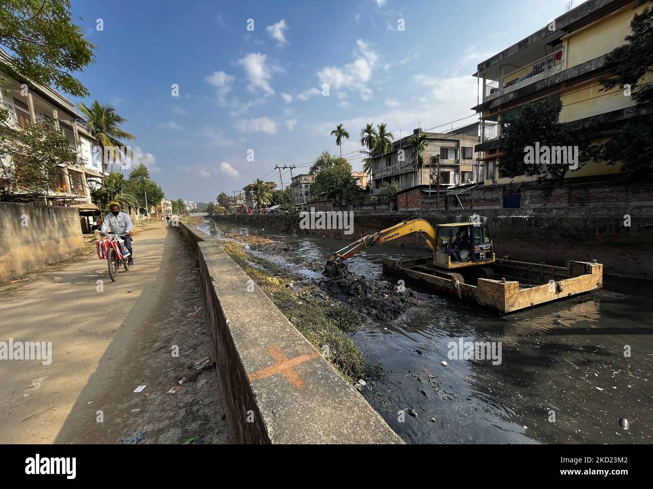 Municipality employee cleaning a roadside drain using an excavator in