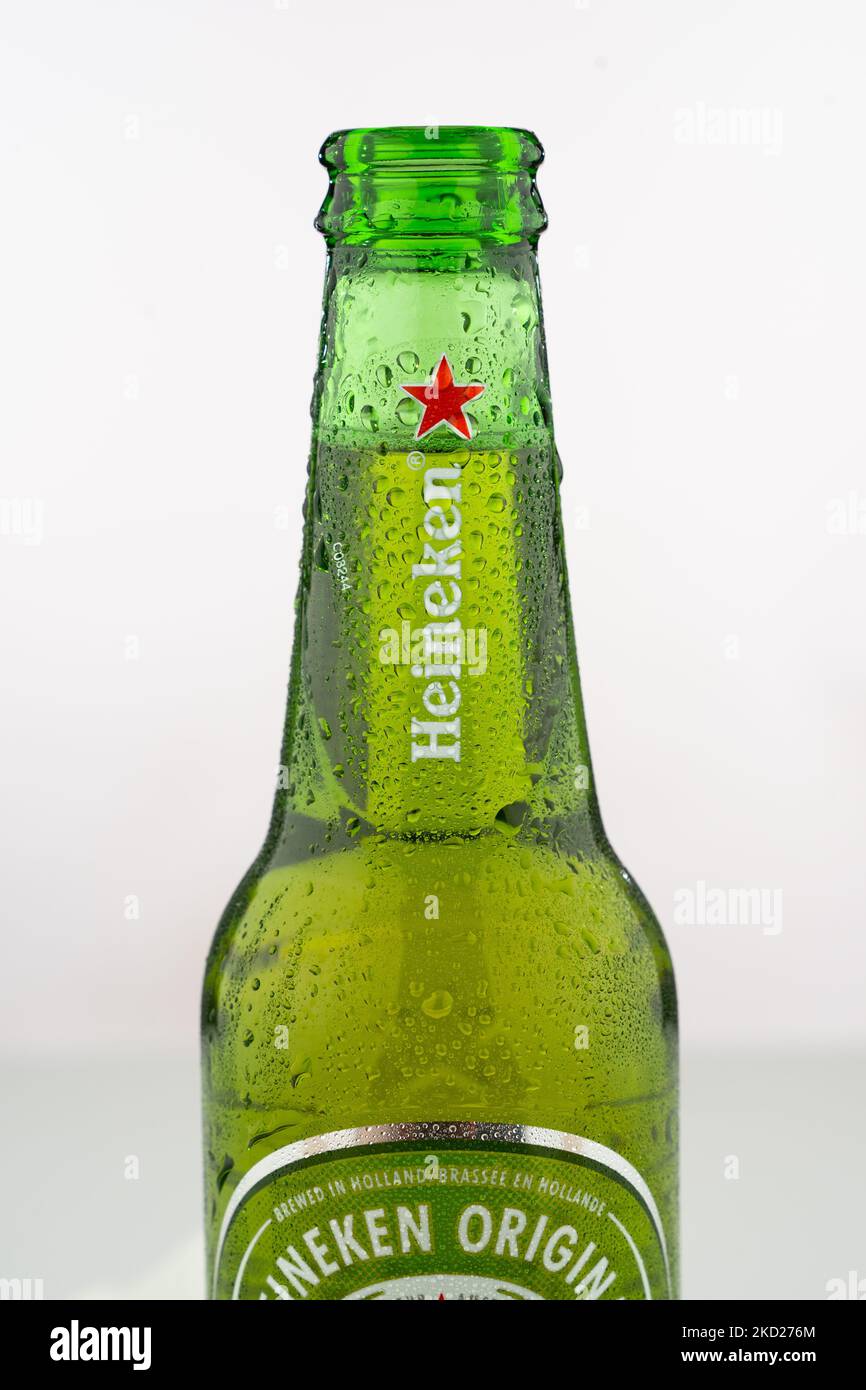 The top half of an open green bottle of Heineken beer with condensation
