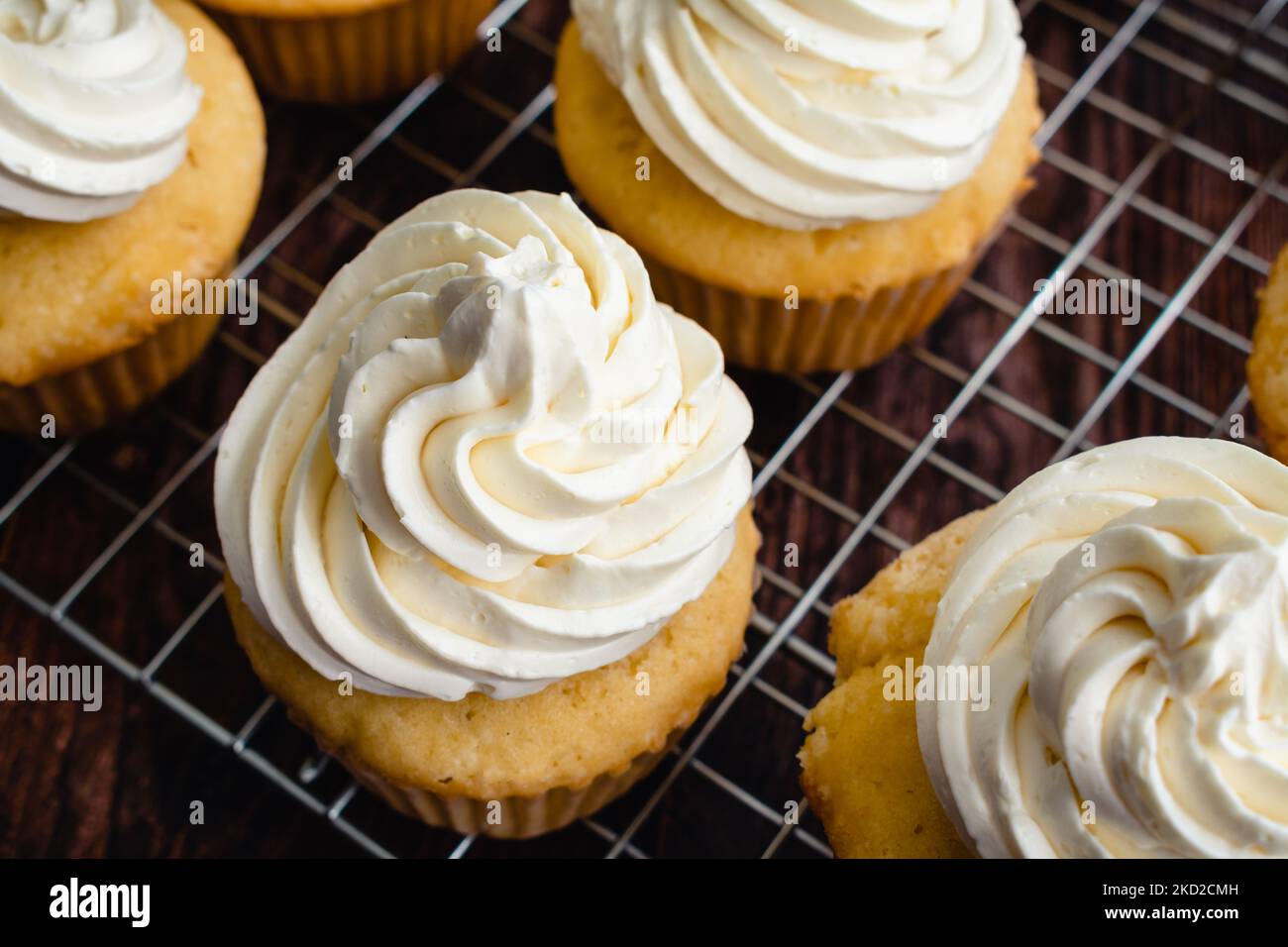 Homemade Vanilla Cupcakes on Wire Cooking Racks: Overhead view of vanilla cupcakes with vanilla buttercream frosting Stock Photo