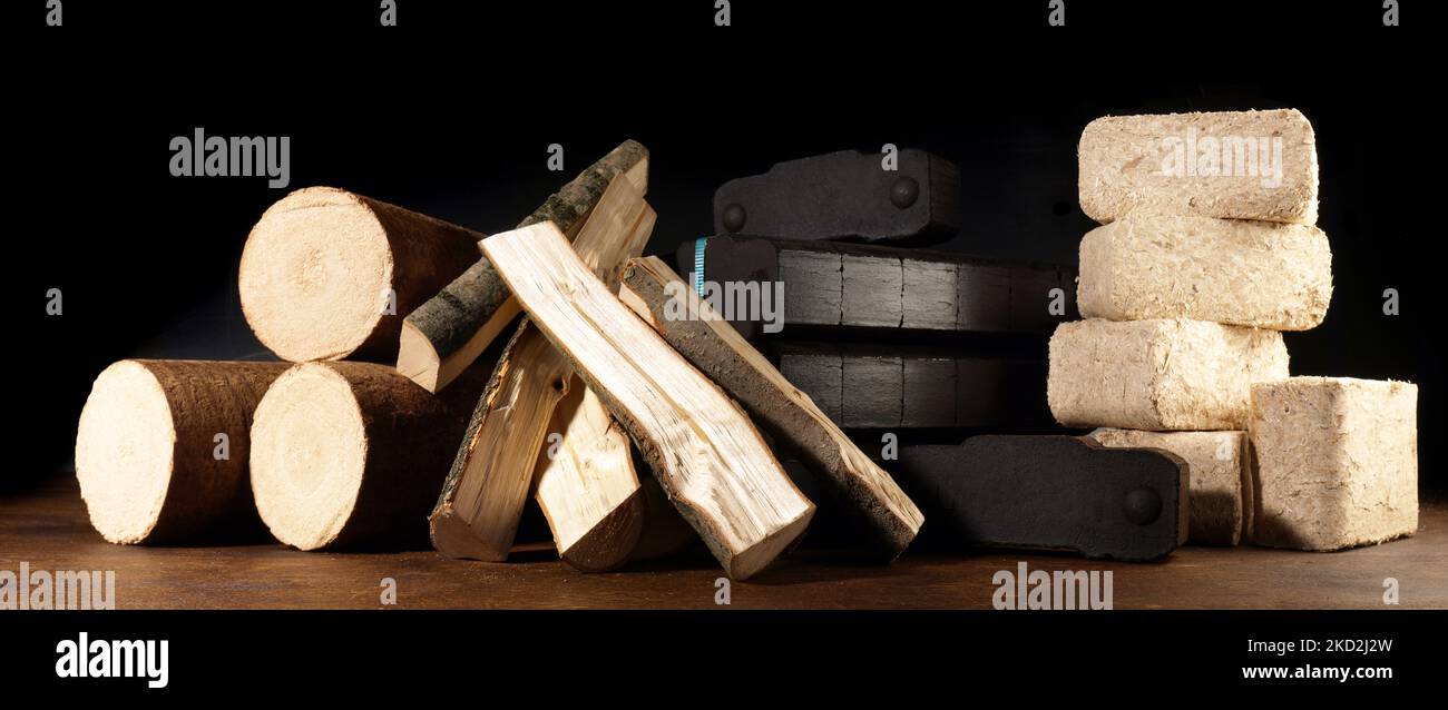 Firewood, Coal and Sawdust Briquettes - Compressed Wood Fire Logs isolated on black Background Stock Photo