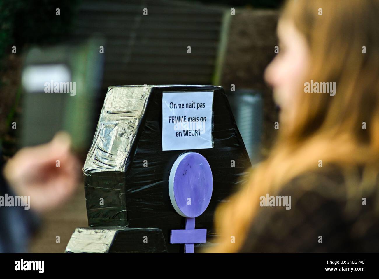 A cardboard coffin reading "we were not born women, we die of it