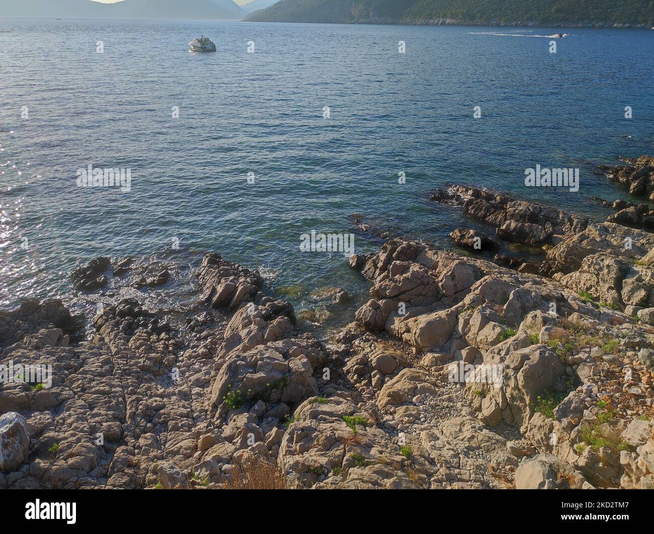 The view of the rocky shore and blue sea with a boat Stock Photo - Alamy