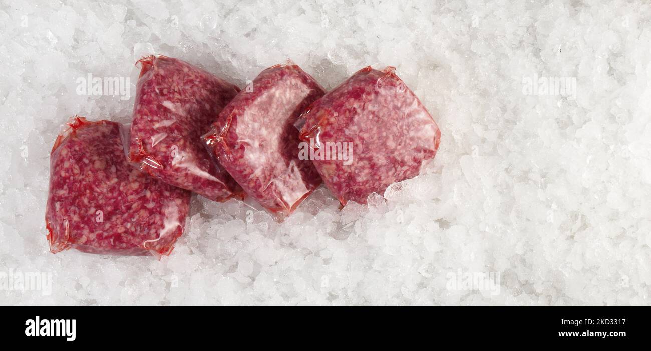 Beef Meat Patties in Vacuum Bags on Ice on white Background - Panorama Stock Photo