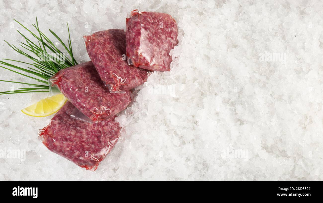 Beef Meat Patties in Vacuum Bags on Ice on white Background - Panorama Stock Photo