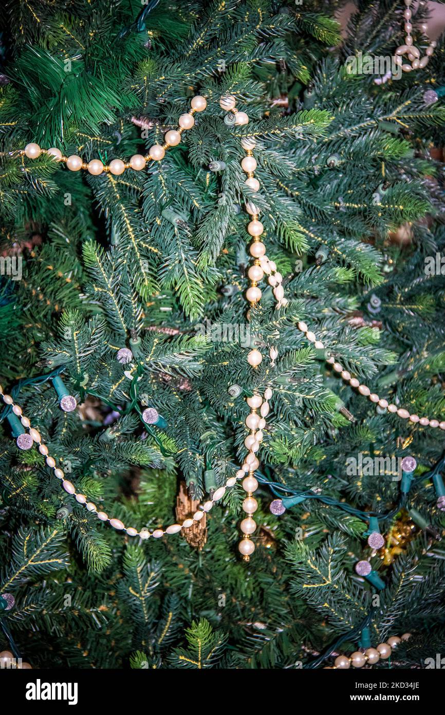 Closeup of artificial Christmas tree with just a few lights and a sting of pearls left on it - Taking down for season Stock Photo