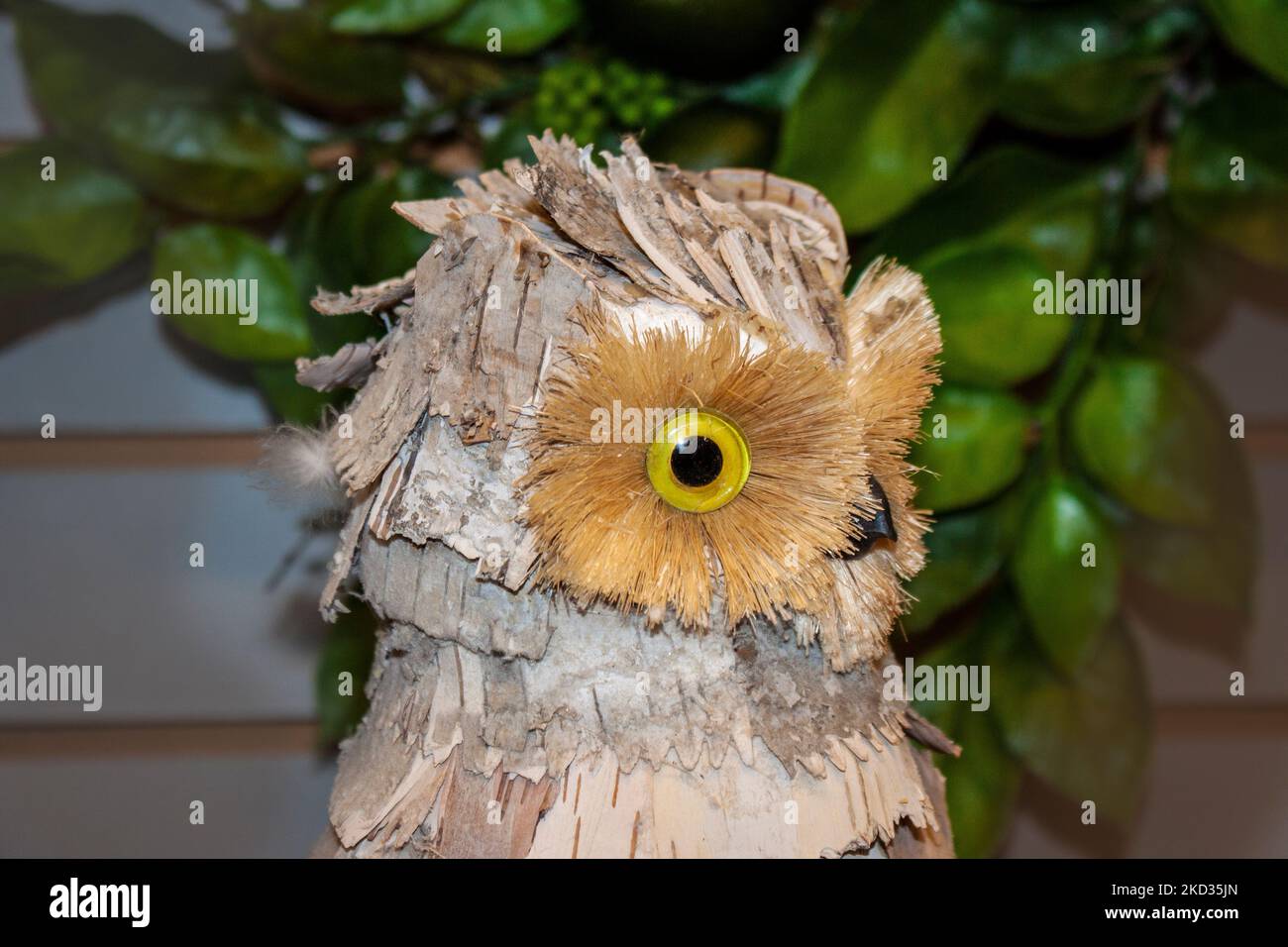 Close-up side view of head of decorative owl made of bark against a dark blurred background Stock Photo